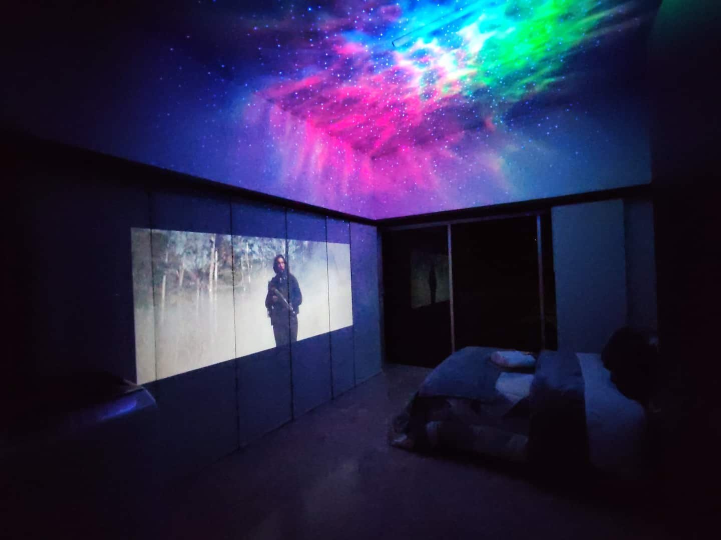 Habitación del Loft Campestre de noche, con el proyector de auroras boreales iluminando el techo